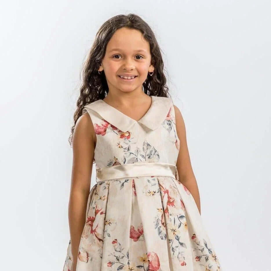 young girl wearing a floral dress from the Baby &amp; Junior Ware collection, smiling at the camera