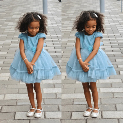 Bright Flower Girls Formal Dress worn by a young girl with curly hair, featuring cap sleeves, tulle skirt, and flower detail.