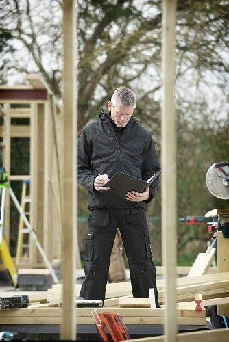 Mens Tuffstuff Extreme Work Trousers - 700 worn by a man reviewing plans on a construction site.