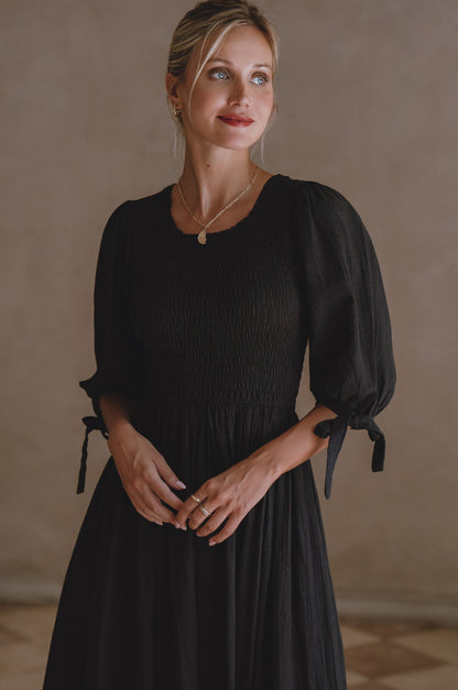 Freya Smocked Linen Midi Dress featuring a smocked bodice and tie up puffy sleeves in a stylish black design.