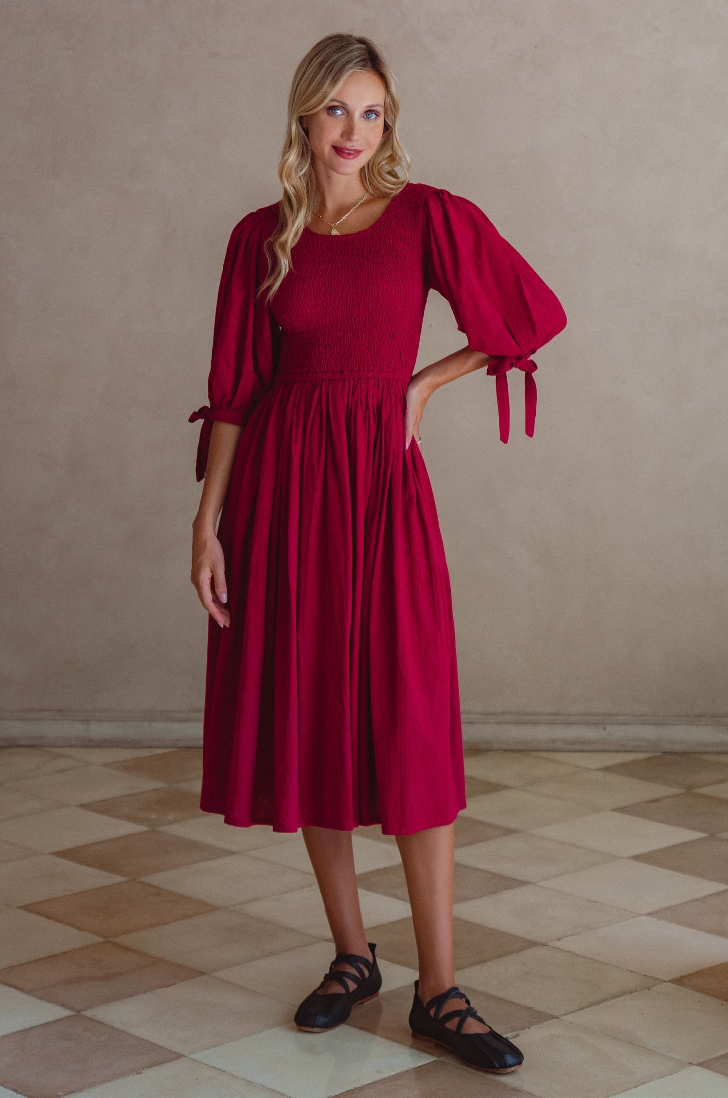 Freya Smocked Linen Midi Dress featuring a smocked bodice and tie up puff sleeves in a rich red color.