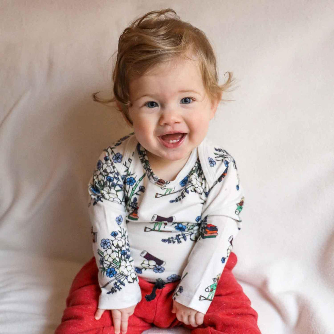 Smiling baby wearing Floral White Baby Onesie with floral designs, showcasing joy and comfort.