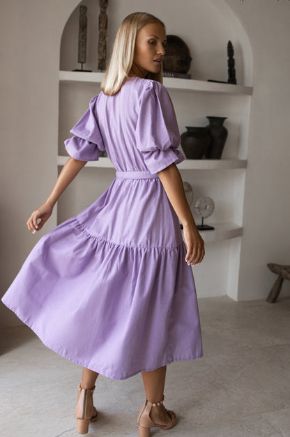 Peony Midi Dress (Sale) - model wearing a lavender midi dress with gathered puff sleeves and matching belt, showcasing back view.