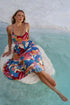 Woman relaxing in the water wearing Sea Dreamer Strappy Midi Dress, showcasing vibrant colors and summer vibes.