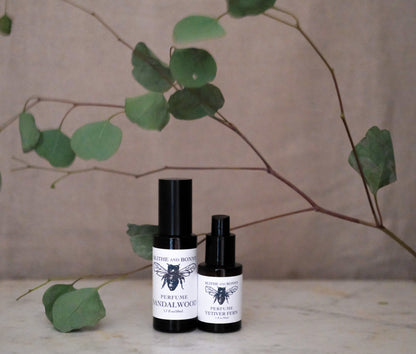 Petite Perfume in amber bottles with sandalwood scent surrounded by eucalyptus leaves.