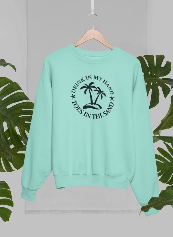 Drink In My Hand Toes In The Sand Sweat Shirt displayed on hanger with tropical leaves backdrop.