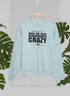 God Is Great Dogs Are Good And People Are Crazy Sweat Shirt in light blue with black text displayed among greenery.