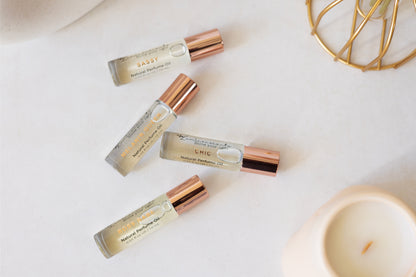 For Her Perfume Oil Roll-On bottles arranged elegantly on a marble surface, showcasing natural fragrances.