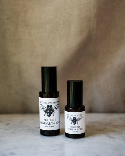 Grand Perfume collection featuring sandalwood and vetiver fern in sleek black glass bottles.